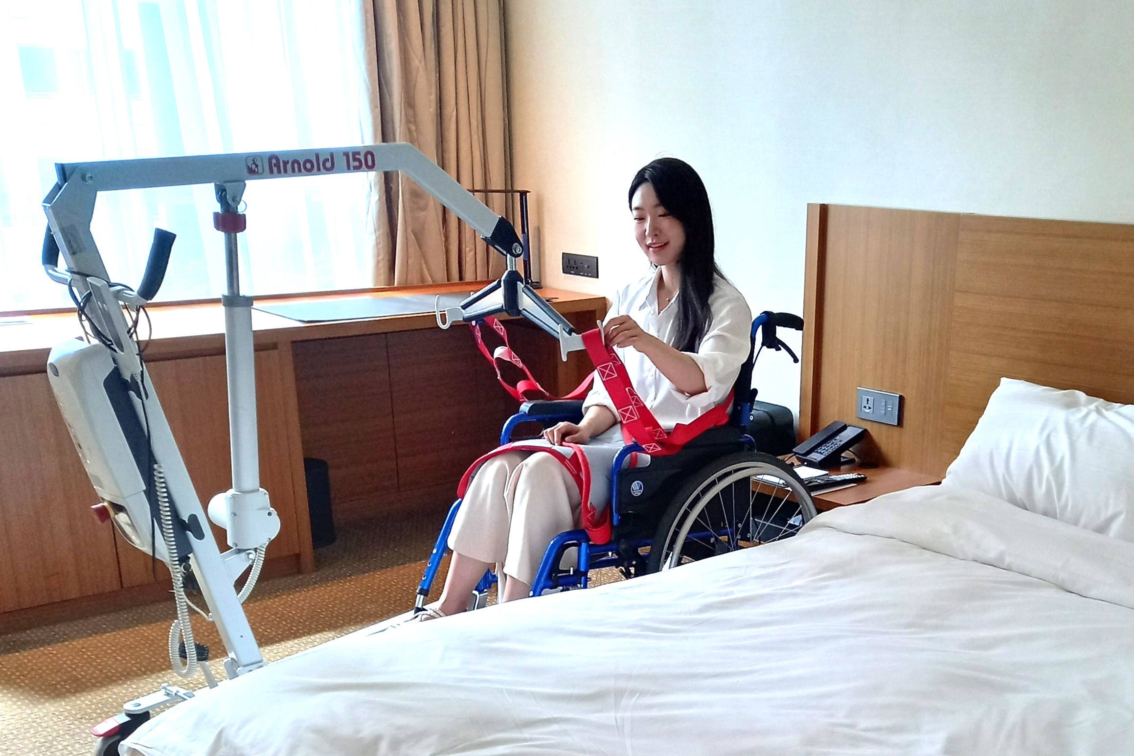 A woman using a portable wheelchair lift inside a hotel room
